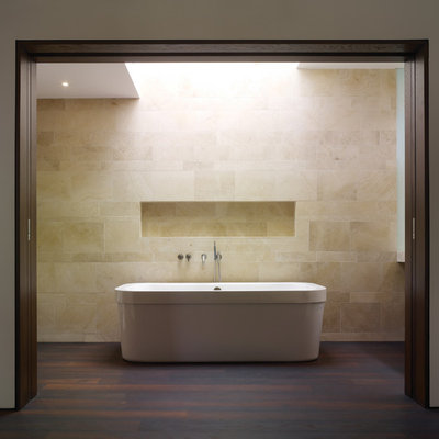 Freestanding bathtub - mid-sized modern beige tile and limestone tile dark wood floor freestanding bathtub idea in Los Angeles with an integrated sink, flat-panel cabinets, dark wood cabinets, a one-piece toilet and white walls