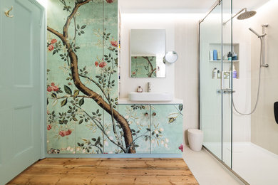 Example of a mid-sized gray tile light wood floor sliding shower door design in London with flat-panel cabinets, white walls, a vessel sink and white countertops