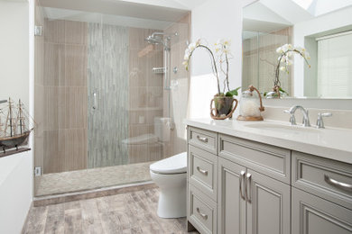 Example of a mid-sized transitional master gray tile and porcelain tile porcelain tile and gray floor alcove shower design in Vancouver with recessed-panel cabinets, gray cabinets, a one-piece toilet, gray walls, an undermount sink, quartz countertops, a hinged shower door and white countertops
