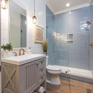 Ispirazione per una stanza da bagno country di medie dimensioni con piastrelle blu, piastrelle di vetro, pareti beige, pavimento in legno massello medio e porta doccia a battente