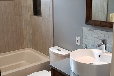 Example of a mid-sized trendy gray tile and porcelain tile porcelain tile and gray floor bathroom design in Kansas City with furniture-like cabinets, medium tone wood cabinets, a two-piece toilet, gray walls, a vessel sink and solid surface countertops