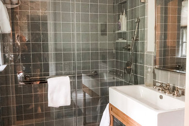 Small transitional blue tile and ceramic tile ceramic tile and white floor walk-in shower photo in Milwaukee with furniture-like cabinets, light wood cabinets, a wall-mount toilet, white walls, a vessel sink and a hinged shower door
