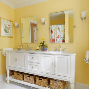 Immagine di una stanza da bagno country con lavabo a consolle, consolle stile comò, ante bianche, top in marmo, vasca ad alcova, vasca/doccia, WC a due pezzi, piastrelle bianche, piastrelle in pietra, pareti gialle e pavimento in marmo