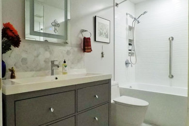Bathroom - mid-sized contemporary 3/4 white tile and ceramic tile porcelain tile and gray floor bathroom idea in Other with flat-panel cabinets, gray cabinets, a one-piece toilet, gray walls, a trough sink, solid surface countertops and white countertops