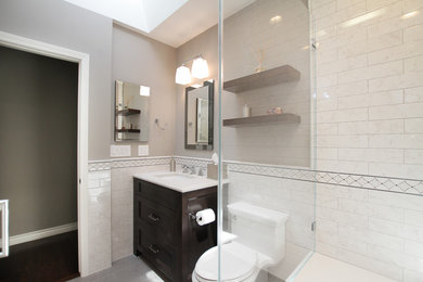 Walk-in shower - mid-sized transitional 3/4 gray tile and porcelain tile porcelain tile and gray floor walk-in shower idea in Los Angeles with recessed-panel cabinets, dark wood cabinets, a one-piece toilet, gray walls, an undermount sink, quartz countertops and a hinged shower door