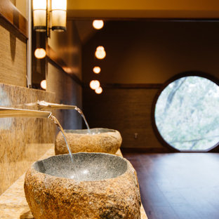 This is an example of a modern master bathroom in Nashville with furniture-like cabinets, medium wood cabinets, a japanese tub, a shower/bathtub combo, a wall-mount toilet, gray tile, pebble tile, grey walls, a vessel sink, marble benchtops, a hinged shower door, yellow benchtops, a niche, a double vanity, a built-in vanity, decorative wall panelling, medium hardwood floors and brown floor.