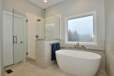 На фото: большая главная ванная комната в стиле модернизм с фасадами в стиле шейкер, черными фасадами, отдельно стоящей ванной, душем в нише, раздельным унитазом, серой плиткой, керамической плиткой, белыми стенами, полом из керамической плитки, врезной раковиной, мраморной столешницей, бежевым полом, душем с распашными дверями, серой столешницей, сиденьем для душа, тумбой под две раковины и подвесной тумбой с