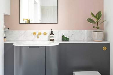 Imagen de cuarto de baño actual con armarios con paneles lisos, puertas de armario grises, paredes rosas, lavabo bajoencimera, suelo gris y encimeras blancas