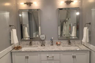 Example of a mid-sized classic master white tile and porcelain tile porcelain tile and gray floor corner shower design in Philadelphia with shaker cabinets, white cabinets, gray walls, an undermount sink and a hinged shower door