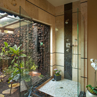 Immagine di una stanza da bagno padronale tropicale di medie dimensioni con doccia aperta, WC monopezzo, piastrelle nere, piastrelle in pietra, pareti beige, pavimento con piastrelle in ceramica, lavabo a bacinella e porta doccia a battente