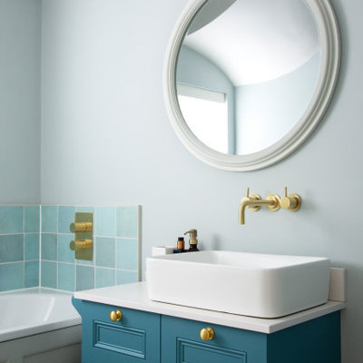 Example of a small transitional 3/4 blue tile, green tile and ceramic tile drop-in bathtub design in London with recessed-panel cabinets, blue cabinets, blue walls, a vessel sink and white countertops