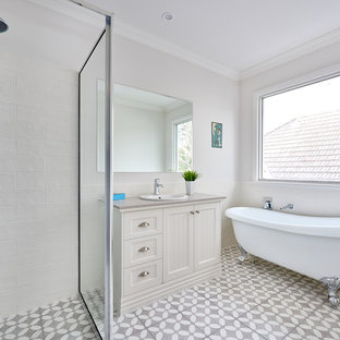This is an example of a beach style 3/4 bathroom in Melbourne with shaker cabinets, beige cabinets, a claw-foot tub, a corner shower, a drop-in sink, grey floor, a hinged shower door and grey benchtops.