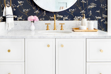 This is an example of a large classic bathroom in Baltimore with flat-panel cabinets, white cabinets, a shower/bath combination, a one-piece toilet, white tiles, marble tiles, blue walls, marble flooring, a submerged sink, marble worktops and white floors.