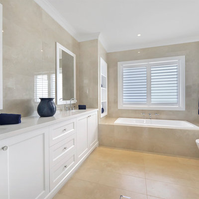 Bathroom - large traditional 3/4 beige tile beige floor bathroom idea in Sydney with shaker cabinets, white cabinets, an undermount sink, a hinged shower door and white countertops