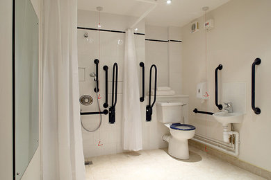 ニューヨークにあるコンテンポラリースタイルのおしゃれな浴室 (壁付け型シンク、バリアフリー、分離型トイレ、白いタイル、セラミックタイル、白い壁、セラミックタイルの床) の写真