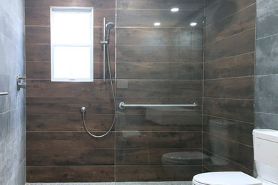 Doorless shower - large contemporary gray tile and porcelain tile porcelain tile doorless shower idea in New York with dark wood cabinets, a two-piece toilet, gray walls, an undermount sink and quartz countertops