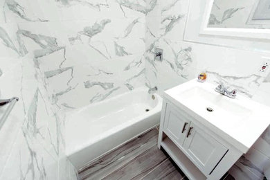 Bathroom - small contemporary white tile and marble tile porcelain tile and gray floor bathroom idea in New York with shaker cabinets, gray cabinets, a two-piece toilet, white walls, an integrated sink, solid surface countertops and white countertops