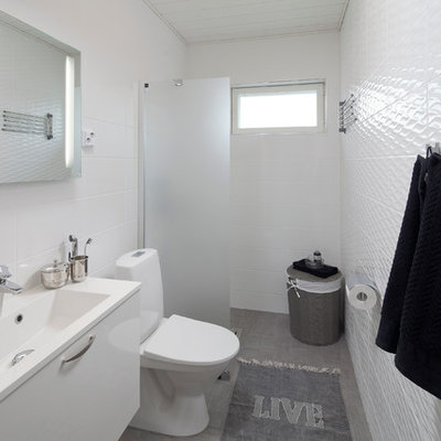 Walk-in shower - scandinavian white tile gray floor walk-in shower idea in Devon with flat-panel cabinets, white cabinets, a two-piece toilet and white walls