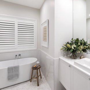 Design ideas for a transitional bathroom in Sydney with shaker cabinets, white cabinets, a freestanding tub, white tile, stone slab, white walls, a drop-in sink, white floor, white benchtops, a single vanity and a floating vanity.