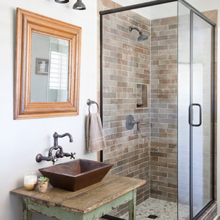 Country 3/4 subway tile and brown tile medium tone wood floor and brown floor corner shower photo in Charleston with furniture-like cabinets, gray walls, a vessel sink, wood countertops, a hinged shower door, brown countertops and distressed cabinets