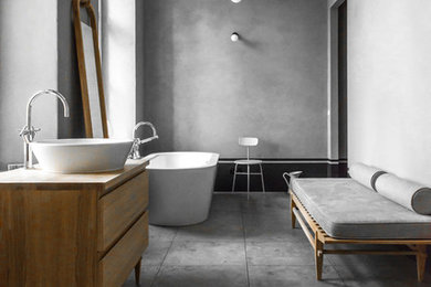 Large contemporary grey and white bathroom in Berlin with medium wood cabinets, a freestanding bath, an alcove shower, a wall mounted toilet, grey tiles, porcelain tiles, grey walls, porcelain flooring, a vessel sink, wooden worktops and flat-panel cabinets.