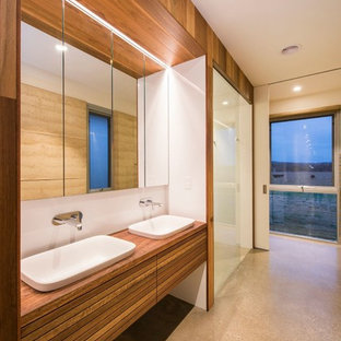 Contemporary bathroom in Other with flat-panel cabinets, medium wood cabinets, a curbless shower, white tile, white walls, concrete floors, a drop-in sink, wood benchtops, grey floor, a hinged shower door and brown benchtops.