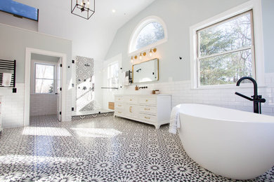 Inspiration for a large mediterranean ensuite wet room bathroom in Boston with shaker cabinets, white cabinets, a freestanding bath, a two-piece toilet, black and white tiles, metro tiles, blue walls, cement flooring, a vessel sink, marble worktops, black floors, a hinged door and white worktops.