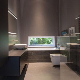 Photo of a medium sized contemporary ensuite bathroom in Oxfordshire with flat-panel cabinets, black cabinets, a built-in bath, a corner shower, grey tiles, porcelain tiles, grey walls, porcelain flooring, a vessel sink, grey floors, black worktops, a single sink and a built in vanity unit.