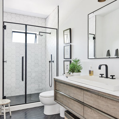 Example of a mid-sized beach style 3/4 white tile and ceramic tile ceramic tile and black floor alcove shower design in Los Angeles with a one-piece toilet, white walls, a drop-in sink, quartz countertops, a hinged shower door, white countertops, flat-panel cabinets and light wood cabinets