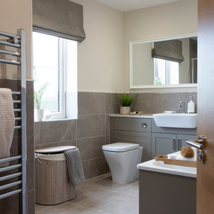 Photo of a traditional bathroom in Hampshire with shaker cabinets, grey cabinets, a one-piece toilet, grey tiles, beige walls, grey floors and white worktops.