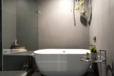 デンバーにあるコンテンポラリースタイルのおしゃれな浴室 (置き型浴槽、コーナー設置型シャワー、グレーの壁、グレーの床、開き戸のシャワー) の写真