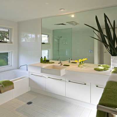 Trendy white tile and ceramic tile ceramic tile alcove bathtub photo in Brisbane with white cabinets, flat-panel cabinets and white walls