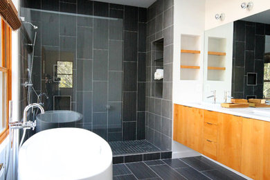 Imagen de cuarto de baño contemporáneo con puertas de armario de madera clara, bañera exenta y paredes blancas