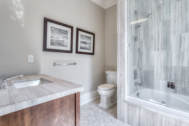 Example of a mid-sized transitional kids' gray tile and stone tile mosaic tile floor drop-in bathtub design in Toronto with open cabinets, light wood cabinets, a one-piece toilet, beige walls, an undermount sink and marble countertops