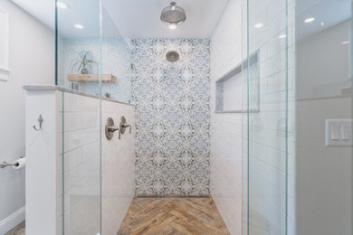 Photo of a large classic ensuite bathroom in Boston with shaker cabinets, white cabinets, a built-in shower, multi-coloured tiles, porcelain tiles, grey walls, porcelain flooring, a submerged sink, marble worktops, brown floors, a hinged door, white worktops, double sinks and a freestanding vanity unit.