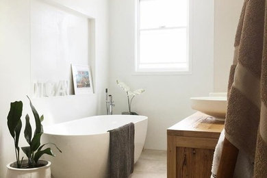 ウーロンゴンにある中くらいなコンテンポラリースタイルのおしゃれな浴室 (中間色木目調キャビネット、置き型浴槽、白い壁、セメントタイルの床、ベッセル式洗面器、木製洗面台) の写真
