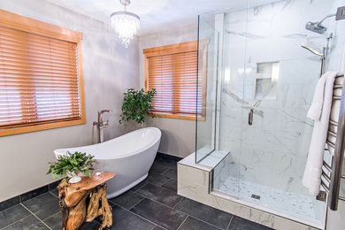 Cette photo montre une salle de bain principale chic avec un placard à porte shaker, des portes de placard blanches, une baignoire indépendante, un carrelage gris, des carreaux de porcelaine, un mur gris, un sol en carrelage de porcelaine et une vasque.