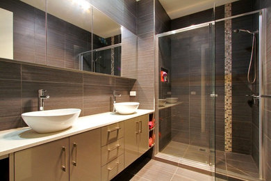 Bild på ett mellanstort funkis badrum med dusch, med luckor med upphöjd panel, grå skåp, en dubbeldusch, grå kakel, keramikplattor, grå väggar, klinkergolv i keramik, ett piedestal handfat, granitbänkskiva, grått golv och dusch med gångjärnsdörr