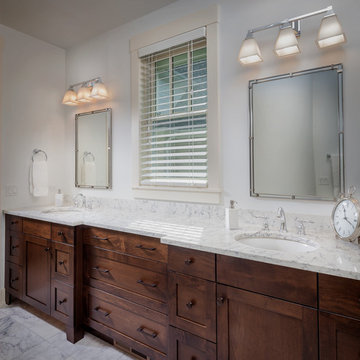 His and her sinks with Carrara marble floor and dark wood cabinetry