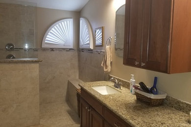 Klassisk inredning av ett mellanstort flerfärgad flerfärgat badrum med dusch, med luckor med upphöjd panel, skåp i mörkt trä, en hörndusch, beige väggar, ett undermonterad handfat, granitbänkskiva och med dusch som är öppen