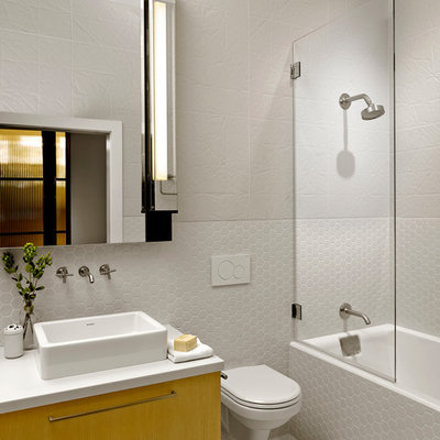Bathroom - mid-sized industrial white tile bathroom idea in San Francisco with a vessel sink, flat-panel cabinets, a wall-mount toilet, white walls and yellow cabinets