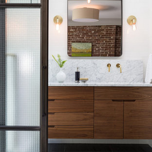 Modern inredning av ett en-suite badrum, med släta luckor, skåp i mellenmörkt trä, en dusch i en alkov, vit kakel, keramikplattor, vita väggar, skiffergolv, ett undermonterad handfat, marmorbänkskiva, grått golv och dusch med gångjärnsdörr