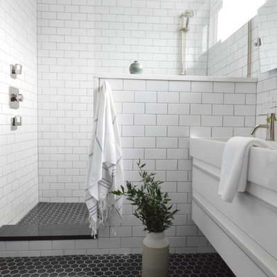 Bathroom - mid-sized modern master white tile and subway tile ceramic tile and black floor bathroom idea in New York with flat-panel cabinets, white cabinets, a one-piece toilet, black walls, an integrated sink, solid surface countertops and white countertops