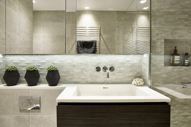 Réalisation d'une salle de bain avec un carrelage gris, un carrelage de pierre, un mur gris, un plan de toilette en quartz modifié et un lavabo intégré.