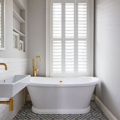 Danish white tile and subway tile cement tile floor and blue floor freestanding bathtub photo in London with open cabinets, gray walls and an integrated sink