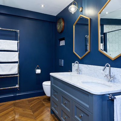 Example of a small trendy kids' white tile and mosaic tile light wood floor and brown floor bathroom design in London with furniture-like cabinets, blue cabinets, a wall-mount toilet, blue walls, a drop-in sink and marble countertops