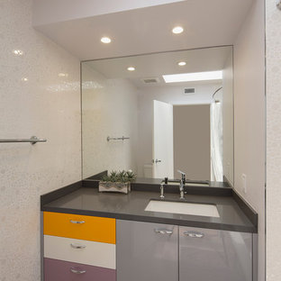 Photo of a contemporary 3/4 bathroom in Los Angeles with an undermount sink, flat-panel cabinets, grey cabinets, a shower/bathtub combo, white tile, mosaic tile, white walls, limestone benchtops and light hardwood floors.