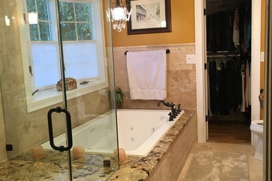 Drop-in bathtub - large traditional master beige tile and stone tile travertine floor drop-in bathtub idea in New York with raised-panel cabinets, dark wood cabinets, a two-piece toilet, orange walls, an undermount sink and granite countertops