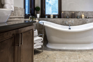 Cette image montre une salle de bain principale traditionnelle en bois brun de taille moyenne avec un placard en trompe-l'oeil, une baignoire indépendante, une douche double, un carrelage de pierre, un sol en marbre, une vasque et un plan de toilette en verre.