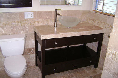 Small elegant 3/4 beige tile ceramic tile bathroom photo in Los Angeles with a vessel sink, flat-panel cabinets, dark wood cabinets, tile countertops, a two-piece toilet and beige walls